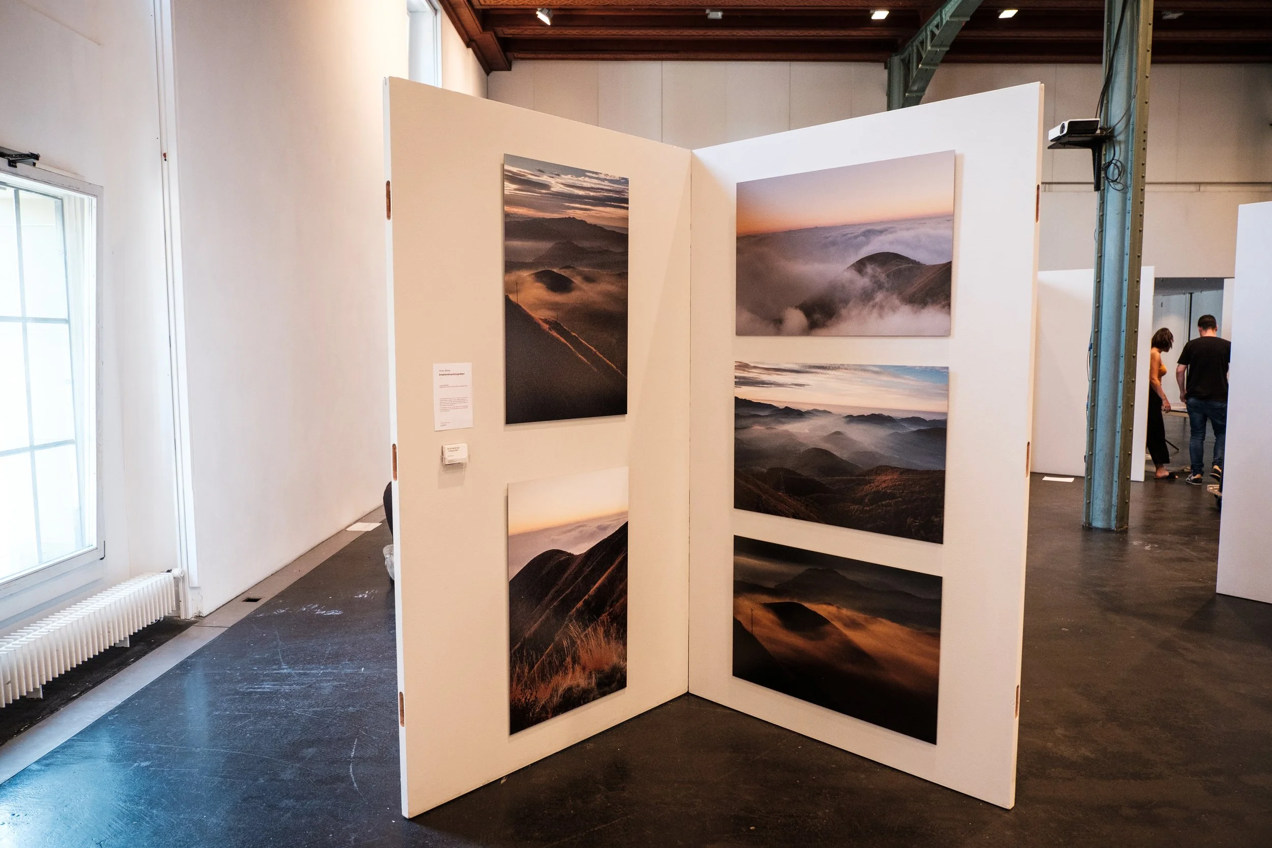Fotowand mit Landschaftsbildern von Bergen und Nebel in einer Kunstgalerie