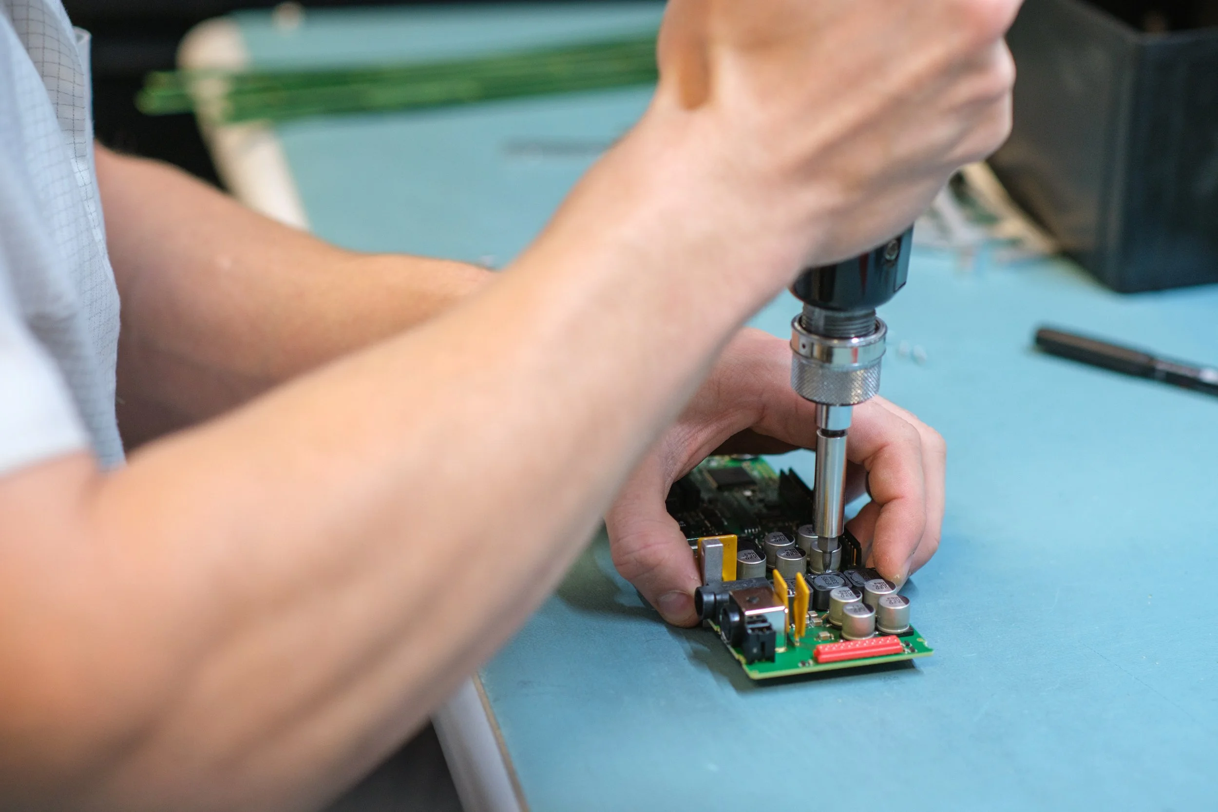 Person verwendet einen Schraubenzieher, um eine elektronische Leiterplatte zu reparieren.